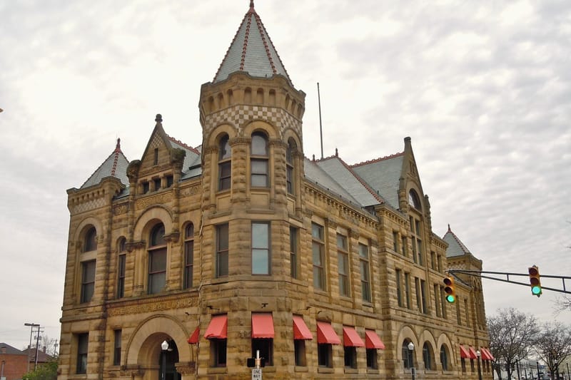 A nineteenth century sandstone municipal building with a corner tower.