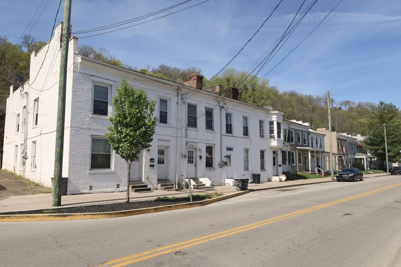 A row of attached houses along a quiet street under a clear sky.
