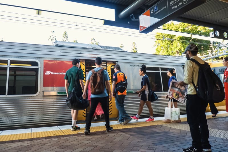 Commuters board a train at a city station platform.